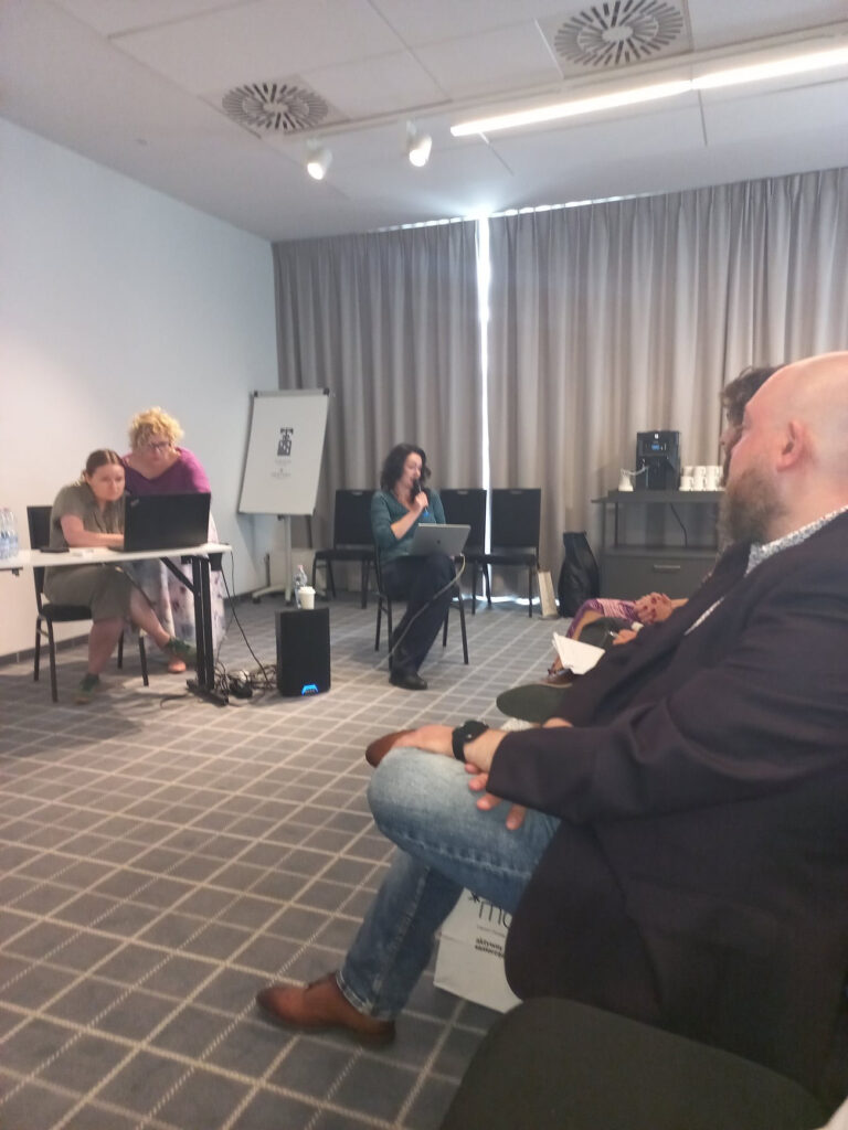 trzy kobiety prowadzące konferencję i mężczyzna z widowni