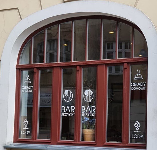 Okno w budynku. Napisy na szybie: Bar Jeżycki, obiady domowe, lody.