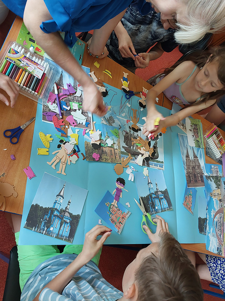 Kobieta i 2 dzieci coś naklejają na brystolu