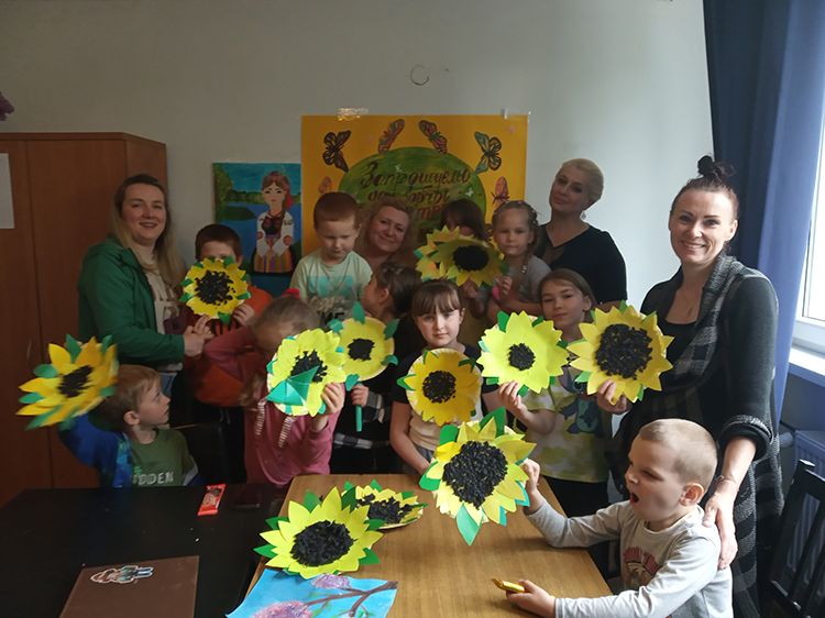 Grupa kobiet i dzieci, pokazują słoneczniki z papieru